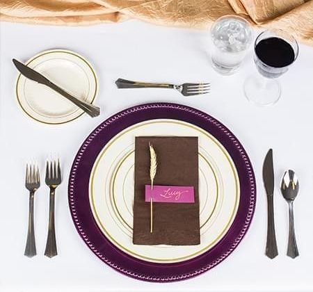 Proper table setting with disposable plates, utensils, folded napkins, and glasses, complemented by place cards.