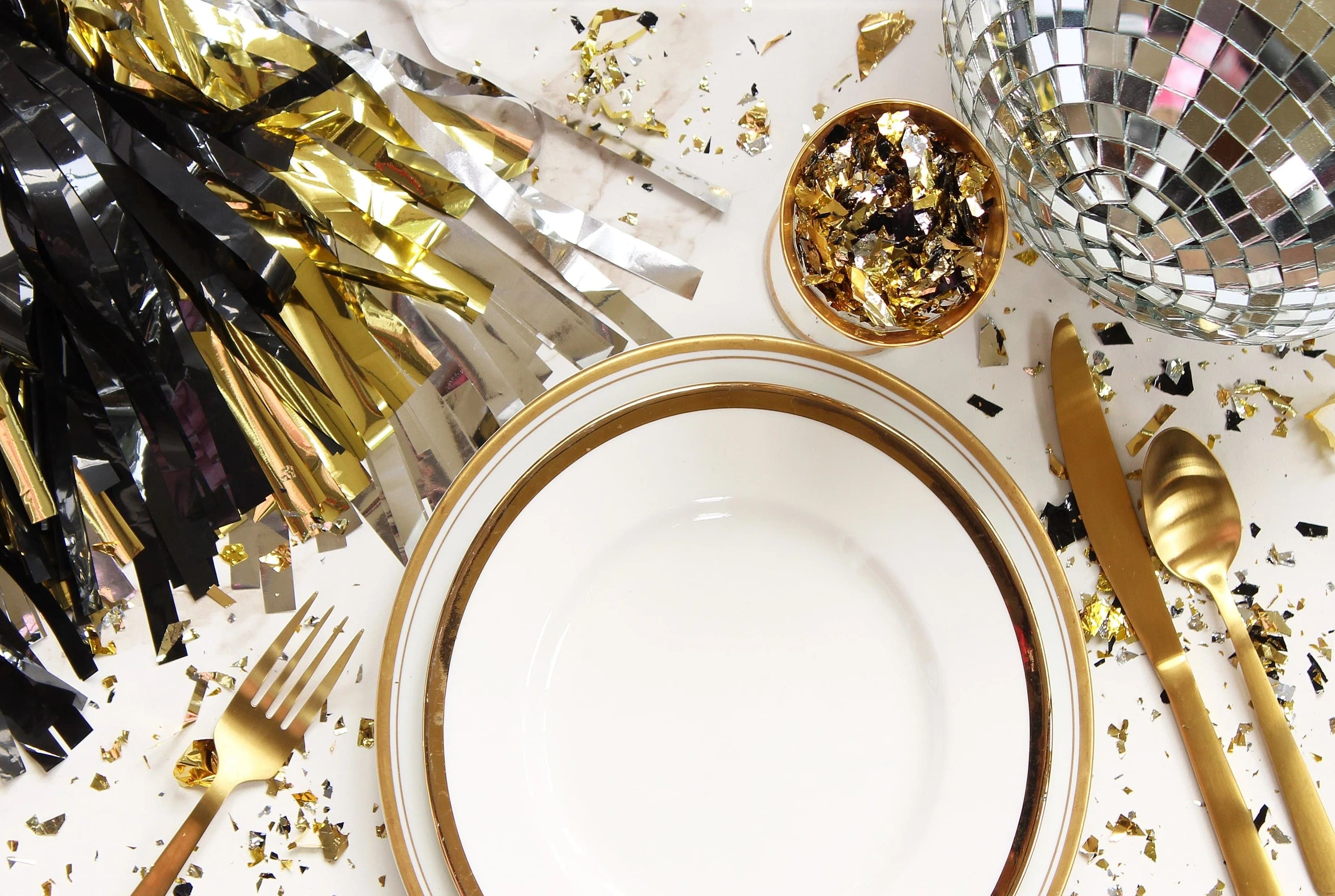 Elegant table setting adorned with gold and black decorations, perfect for New Years Eve party ideas.