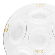 Introducing the Clear with Gold Round Section Tray Disposable Plastic Seder Plate (12"). This elegant plate features six indents for traditional symbolic foods, each labeled in Hebrew with gold lettering. Its clear design and stylish gold accents make it a perfect addition to your Passover table.