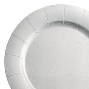 A close-up shot of a Silver Round Disposable Paper Charger Plate (13"). The plate features a slightly textured surface with visible creases that radiate outward from the center to the edge, giving it a segmented appearance. The white background accentuates the plate's simplicity and sophistication.