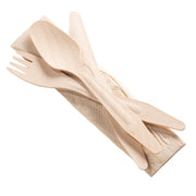 A set from Kaya Collection's Natural Birch Wood Eco-Friendly Disposable Cutlery Set with Napkin, which includes a fork, knife, and spoon made from natural birch wood, is placed on a folded beige napkin. The utensils showcase a rustic appearance with visible light wood grain texture. The accompanying napkin features a subtle, textured pattern.