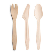 Three items from the Kaya Collection's Natural Birch Eco Friendly Disposable Wooden Cutlery Set are displayed side by side on a white background: a fork with shortened tines on the left, a serrated knife in the middle, and a spoon with a rounded bowl on the right.