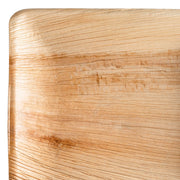 Close-up of a light wooden surface showing detailed grain and texture, with subtle natural color variations. The corner of the wood is rounded, and the surface appears polished, much like the quality found in Kaya Collection's Square Palm Leaf Eco Friendly Disposable Dinner Plates (10").