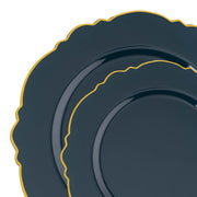 Two stacked Navy with Gold Rim Round Blossom plates showcase dark blue hues with scalloped edges and golden trim. These disposable dinnerware items feature an elegant, polished finish and sophisticated design. The contrast between the navy and gold imparts a luxurious appearance, ideal for an elegant table setting.