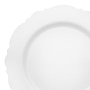 The Solid White Round Blossom Disposable Plastic Dinner Plates (10.25") are depicted against a white background. Ideal for weddings and parties, these plates feature a clean and elegantly empty design with scalloped edges.