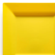 A close-up of the corner of a vibrant yellow square plate from the Kaya Collection's 9.5" Yellow Square Plastic Dinner Plates. The plate features sharp, clean edges and a minimalistic design, set against a white background to create a bright, modern contrast. These elegant disposable dinnerware pieces are both sturdy and BPA-free, making them perfect for any occasion.