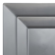 A close-up of two overlapping plates from the Kaya Collection Silver Square Plastic Plates Dinnerware Value Set, both featuring a matte gray finish, sharp, clean lines, and a modern, minimalist design. These elegant disposable plates create a layered geometric visual against the white background.