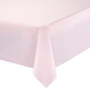 A close-up of a pastel pink rectangular plastic tablecloth draped over the edge of a table. The material hangs smoothly and forms a neat fold at the corner, showcasing the soft texture and clean finish of the disposable tablecloth.