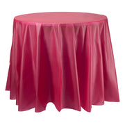 A round table adorned with a striking burgundy, disposable plastic tablecloth that extends smoothly down to the floor. The sleek material reflects light, providing a glossy finish. These Burgundy Round Disposable Plastic Tablecloths (84") bring a vivid and elegant charm to any table setting.