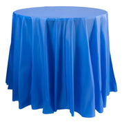 A round table draped with a flowing, vibrant navy tablecloth. The cloth hangs evenly around the table, creating elegant folds and a smooth surface on top. The Navy Round Disposable Plastic Tablecloths (84") extend to the floor, covering the table legs completely.