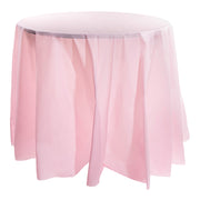 A round table draped with a Pink Round Disposable Plastic Tablecloth (84") that reaches the floor, creating soft, flowing folds around the table. The surface of the table is smooth, and the setting is minimalist with no additional objects or decorations.