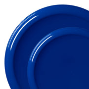 Two overlapping blue plates from the Solid Blue Flat Round Disposable Plastic Dinnerware Value Set are shown on a white background. The plates have a glossy finish, giving them a slightly reflective surface. The larger plate partially obscures the smaller one, highlighting the contrast in their sizes. These BPA-free party plates add a touch of elegance to any setting.