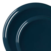 Two overlapping plates from the Navy Flat Round Disposable Plastic Dinnerware Value Set are displayed against a white background. The dark blue plates have a glossy finish, reflecting light and creating bright highlights on their smooth surfaces. The larger plate is partially covered by the smaller one in front, making them ideal for single-party use as disposable plastic dinnerware.