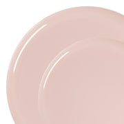 Close-up of two pastel pink plates from the Pink Flat Round Disposable Plastic Dinnerware Value Set, stacked partially on top of each other. The image emphasizes the smooth, glossy surface of this elegant disposable tableware, showcasing their understated round design against a white background.