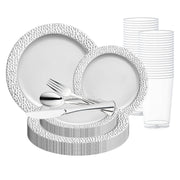 The Smarty had a party White with Silver Hammered Rim Round Plastic Wedding Value Set features plates in two different sizes, making it perfect for a plastic dinnerware set. The set also includes transparent plastic cups stacked neatly and silver plastic cutlery—forks, knives, and spoons—arranged on a smaller plate. These disposable party supplies are ideal for any event.