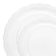 The Kaya Collection Clear Vintage Round Disposable Plastic Dinnerware Value Set features two nested plates with decorative, scalloped edges and subtle embossed patterns. The larger plate sits underneath and is slightly offset, while the smaller plate rests elegantly on top. Both plates boast a classic design that adds sophistication to any setting, making them perfect for fancy disposable dinnerware.