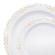 Close-up of two overlapping dinner plates from the Kaya Collection's White with Gold Vintage Rim Round Disposable Plastic Dinnerware Value Set, featuring intricate floral and scroll designs along the scalloped edges. The larger plate sits behind the smaller one, showcasing the elegant and ornate detailing that mimics high-quality plastic party dinnerware.