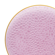 A close-up image of a Kaya Collection Clear Pink with Gold Rim Hammered Glass Disposable Plastic Dinner Plate (10.25"). The plate has a textured, bumpy surface and its edges are rimmed with a thin gold band. The background is plain white, highlighting the plate's intricate design and soft color, perfect for wedding party plates or elegant dinner settings at special events.