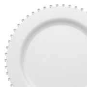 Close-up of a disposable plastic dinner plate from the "White with Silver Pearl String" collection, showcasing a smooth surface and decorated edge with small, clear, round beads. Perfect for weddings and parties, the evenly spaced silver beads around the 10-inch plate's perimeter add a touch of elegance to its simple design.