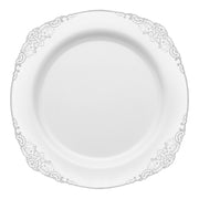 A sophisticated white disposable plastic plate with intricate silver patterns adorning the edges. This elegant tableware is perfectly round and features a delicate, ornate design, while the center remains plain and smooth. The product name is "White with Silver Fancy Round Disposable Plastic Salad Plates (7.5”).