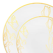 Two dinner plates from the Kaya Collection that feature a refined touch with their intricate, yet simple floral designs in white and gold. These disposable plastic plates have a gold rim adorned with elegant flowers, making them perfect for adding sophistication to any occasion.