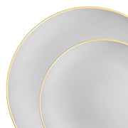 A close-up image captures the edges of two overlapping plates, one partially hidden beneath the other. The elegant set features the Gray with Gold Organic Round Disposable Plastic Dinnerware Value Set by Kaya Collection, highlighting their sophisticated design against a white background.