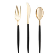 The Kaya Collection Gold with Black Handle Moderno Disposable Plastic Cutlery Set is displayed vertically, showcasing its sleek and modern design. From left to right, the set includes a fork, a serrated knife, and a spoon. The utensils feature shiny gold tops contrasted with matte black handles, making them perfect as stylish disposable cutlery.