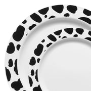 A close-up image showcases an ornamental piece from the White with Black Dalmatian Spots Round Disposable Plastic Dinnerware Value Set. The plate displays irregular black spots on a white background, evoking a cow pattern. This modern and artistic design enhances any table setting with its minimalist two-color scheme, exuding elegance.