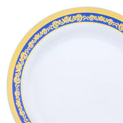 A close-up shot of the White with Blue and Gold Royal Rim Plastic Dinner Plate (10.25"). The edge of this white dinner plate showcases an intricate blue and gold pattern adorned with floral designs, imparting an elegant and sophisticated look. The center of the plate remains plain white.