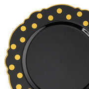 Introducing the Kaya Collection Black with Gold Dots Round Blossom Disposable Plastic Dinner Plates (10.25"), a sleek and stylish black plate adorned with yellow polka dots gracefully lining its wavy, scalloped edge. The evenly spaced dots create a festive and playful border, making it an ideal choice for wedding party plates. The remainder of the plate features a solid, glossy black finish, adding to its elegant appeal.