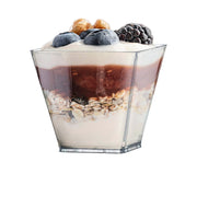 A 3.5 oz. Clear Square Disposable Plastic Mini Cup with a lid, filled with layers of creamy yogurt, granola, and fruit. Topped with blueberries, blackberries, and nuts, the parfait showcases a delicious and healthy breakfast or snack option.